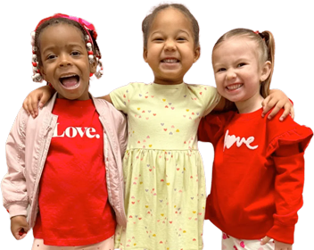 Three smiling kids in colorful shirts pose together in front of house design.